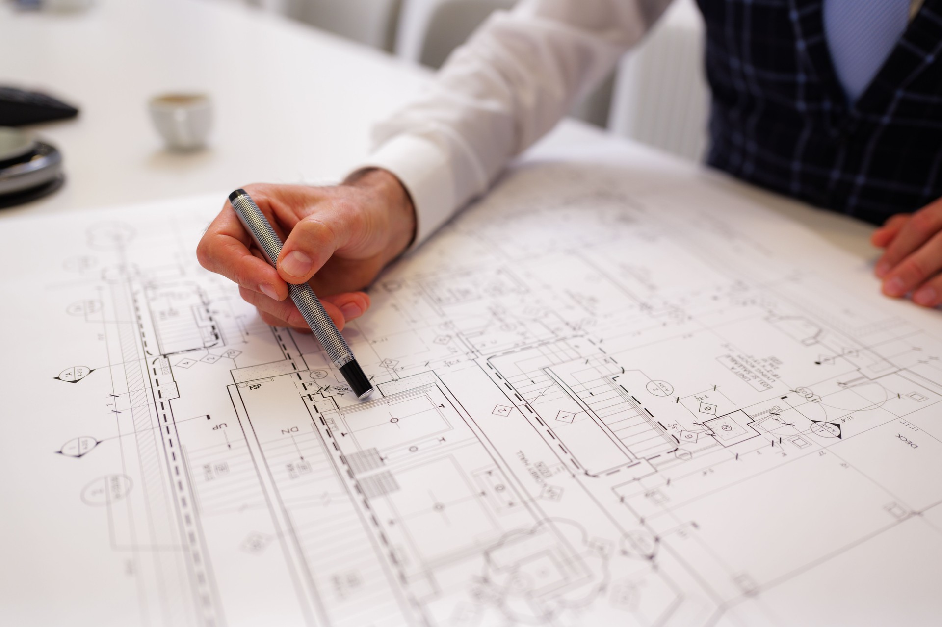 Architect reviewing blueprint on a white table with pen in hand